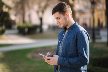 Young man use phone and wireless headphones and print message in social network