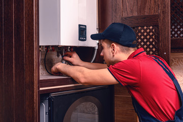 Plumber adjusts gas boiler before operating, professional of his craft