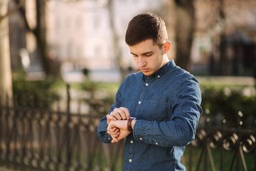 Handsome business man look at the watch in the city. Man ajust the exact time on the watch