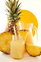 Jug and glass of pineapple juice with fruits on white background. Sweet and tasty yellow is a useful vitamin. Summer composition
