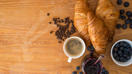 Rogaliki croissant z dżemem owocami i kawą leżące na drewnianym blacie - obrazy, fototapety, plakaty