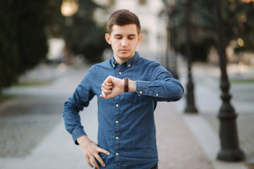 Handsome business man look at the watch in the city. Man ajust the exact time on the watch