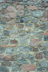 Wall from rubble stone of gray and red color. Decorative texture uneven wall surface from real stone
