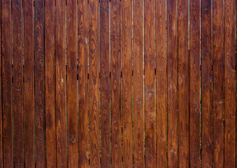 Wooden fence from rough pine oiled dark planks verticaly attached . Horizontal wood texture