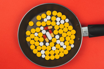top view of pills in frying pan against red background