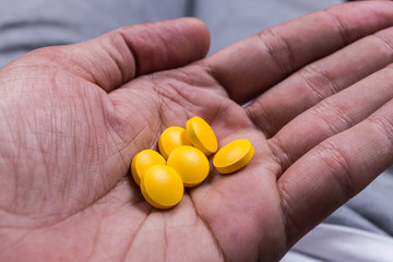 hand holding yellow pharmaceutical medicine pills