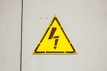 Yellow sign danger electricity on steel door in switchboard. Texture with paint stains and rusty