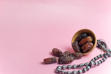 Ramadan Kareem Festival, Dates at bowl with rosary on pink background
