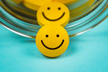 yellow smiley pills spilling out of a toppled pill bottle