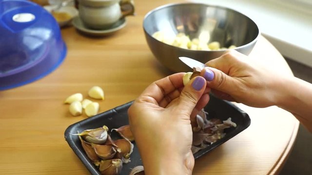 Cleaning garlic with a knife.