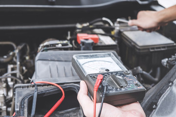 Services car engine machine concept, Automobile mechanic repairman hands repairing a car engine automotive workshop with a wrench and digital multimeter testing battery, car service and maintenance
