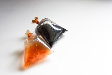 dipping soy sauce and chilli sauce in a plastic bag that is tightly packed with rubber.,black sauce...