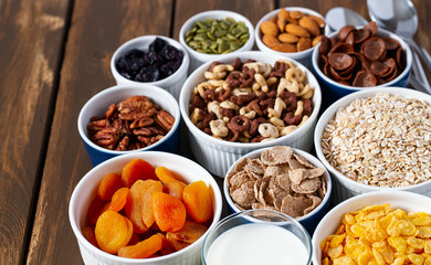 various cereals, nuts and dried fruits on wooden surface