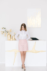 Portrait of a beautiful young businesswoman in a skirt and blouse on a white background in a modern interior