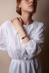 Asian chinese model wearing a rose gold bracelet and white lace dress, presenting the bracelet product