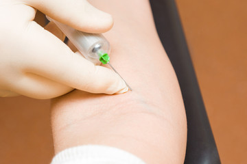 Doctor hand in rubber protective glove using syringe and taking blood from vein of woman arm. Visit to physician at office. Closeup.
