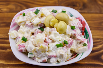Potato salad with marinated mushrooms, sausage, onion and mayonnaise on wooden table