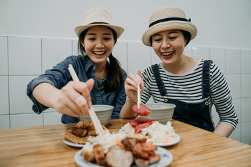 two happy smiling asian girls travelers love delicious food trying taiwanese local meal sitting in...