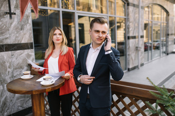 Handsome and Confident Businessman Using Laptop Computer and Technology Gadget Smartphone outdoor Discussing With Beautiful Business Partner .New Modern Business People Lifestyle.