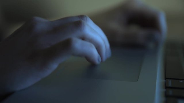 Closeup of a young woman's fingers. She is usig her laptop. Moving camera.