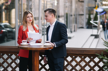 Preparation for meeting. Two young business people standing outside on the city street holding documents looking at each other smiling happy bottom view close-up