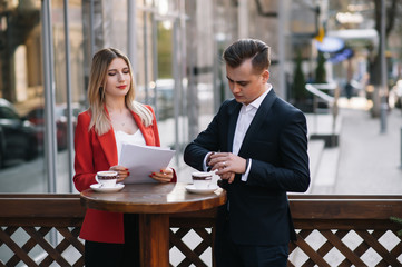 Preparation for meeting. Two young business people standing outside on the city street holding documents looking at each other smiling happy bottom view close-up
