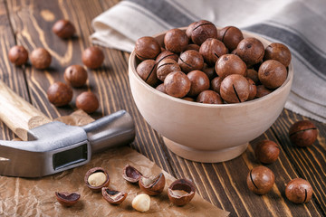 Macadamia nuts in a wooden bowl on a brown background. Food healthy concept.