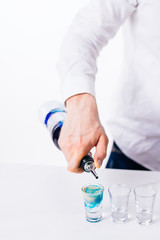 Fototapeta premium Bartender pours alcoholic drink into small glasses on bar. Colorful cocktails at the bar.