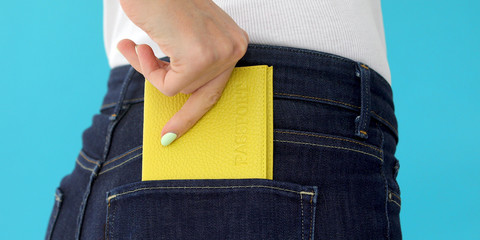 Young woman behind in worn out jeans and passport in a pocket