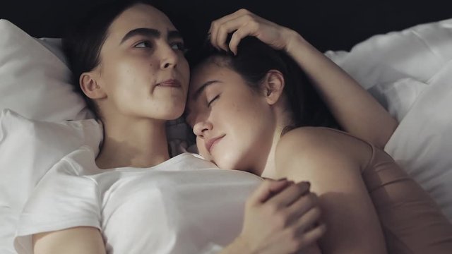 Lesbian couple embracing in the bed at home. Slow motion. Lifestyle, LGBT concept