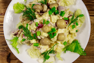 Potato salad with marinated mushrooms, eggs, red onion and mayonnaise on wooden table