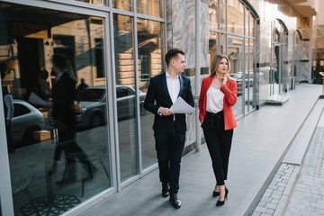 Obraz premium A two young business-people are walking along office building