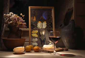 Glass of wine and oranges on the table.