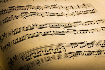 Close-up of sheet music page, in black background