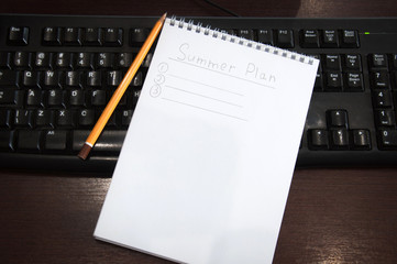 Summer plan. A notepad with notes for the summer is on a computer keyboard.