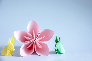 Pink flower from paper origami, next rabbit from paper origami. Easter background, background about creativity, copy space