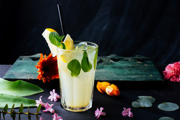 A glass with fresh lemonade on dark table decoratedwith colorful flowers