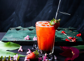 Fresh iced  strawberry juice in glass with mint on dark background