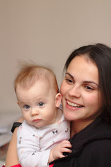 young mother holds her funny, sweet baby in her arms