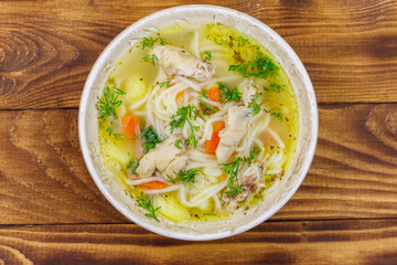 Chicken soup with noodles and vegetables on wooden table. Top view