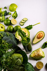 Smoothie drink with avocado, lime and spinach on white wooden background. Raw food and drink.