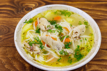 Chicken soup with noodles and vegetables on wooden table