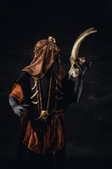 Portrait of a shaman holding a human goat skull in his hands