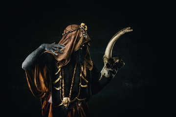 Portrait of a shaman holding a human goat skull in his hands