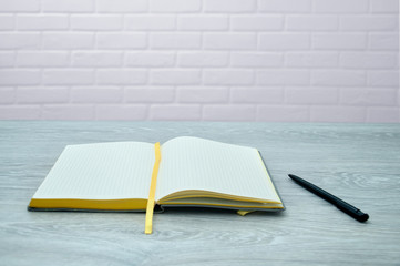 The organizer with the handle lies on a gray wooden table against the background of a white brick wall. Notebook but loft background. Notepad for notes on the background of the wall.