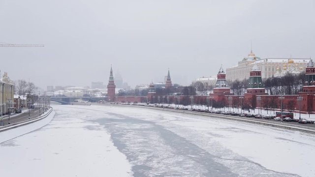 MOSCOW, RUSSIA - DECEMBER, 2018: Handheld real time shot of Kremlin walls and churches and two banks of Moscow river frozen at winter time. Historical brick walls of Kremlin covered with snow