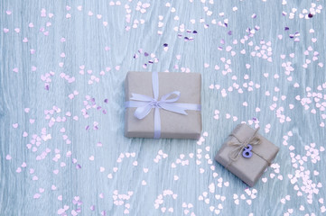 Gift boxes with confetti in the form of hearts on a gray wooden background. Greeting card for March 8.