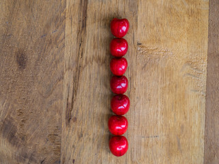 cherry on wooden background as a letter
