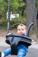 Child with uncertain face on a swing