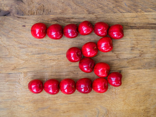 cherry on wooden background as a letter